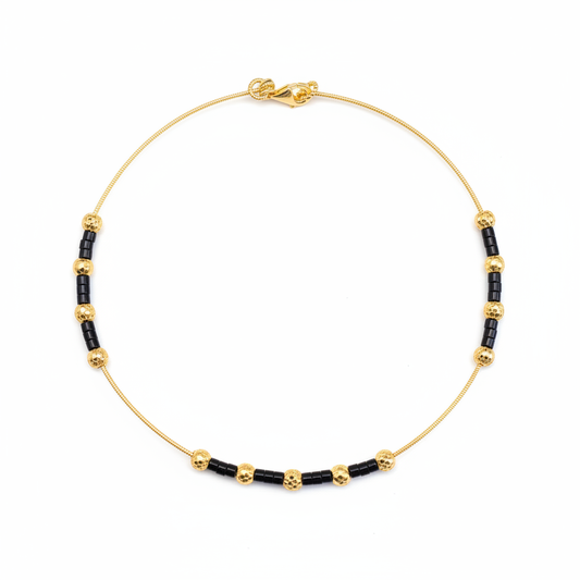 Gold and black beaded necklace on white background