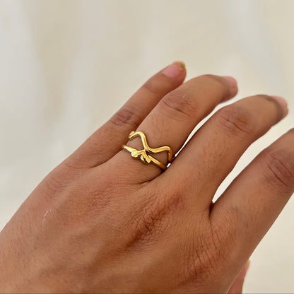Hand wearing a gold abstract snake-shaped ring with an open, flowing design.