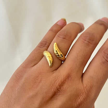 Hand wearing a gold ring with two curved claw-like ends wrapping around the finger.
