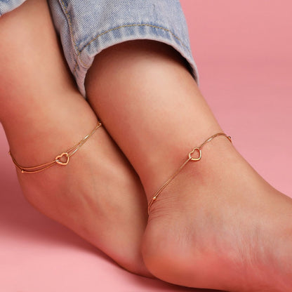 Woman wearing dainty 925 Sterling Silver heart anklets on crossed ankles. Fine women's jewellery – Zavya