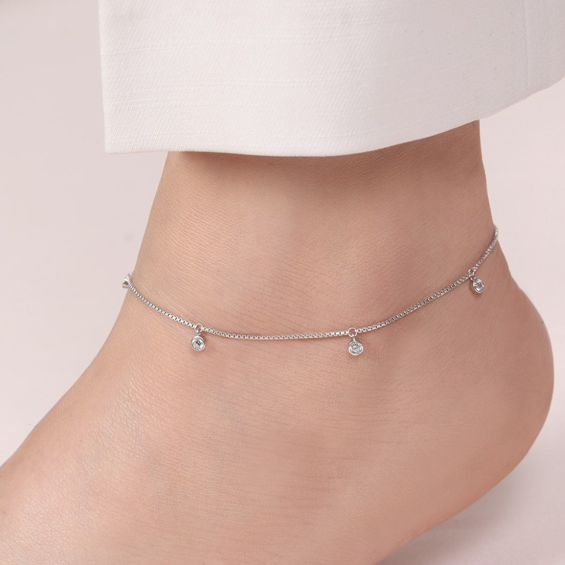 Woman's ankle wearing a delicate CZ drop 925 Sterling Silver anklet. Elegant women's jewellery. – Zavya