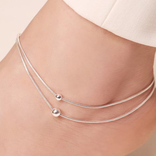 Woman wearing a layered 925 Sterling Silver soft bead chain anklet. Everyday jewellery for women. – Zavya