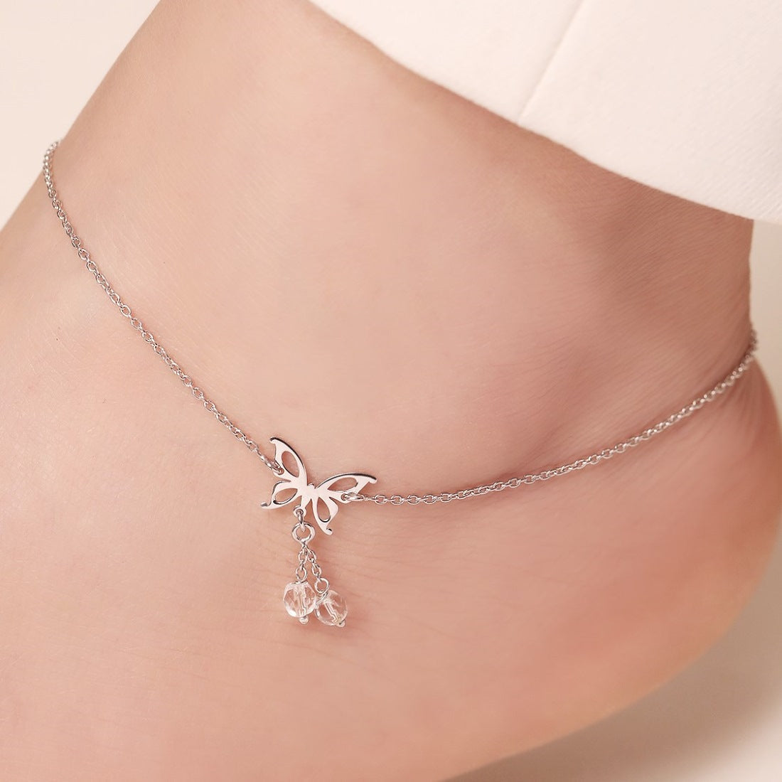 Woman wearing a 925 Sterling Silver butterfly anklet with dangling crystals. Elegant women's jewellery – Zavya