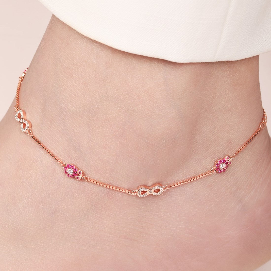 Rose gold 925 Sterling Silver anklet on a woman's ankle with infinity and pink floral CZ details. – Zavya