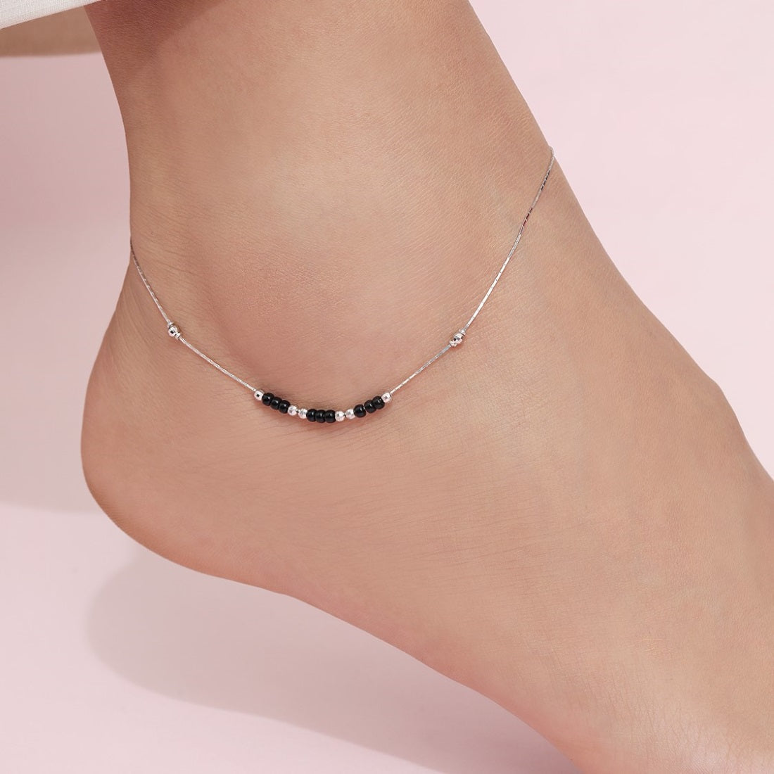 Woman wearing a 925 Sterling Silver anklet with black and silver beads. Fine women's jewellery – Zavya