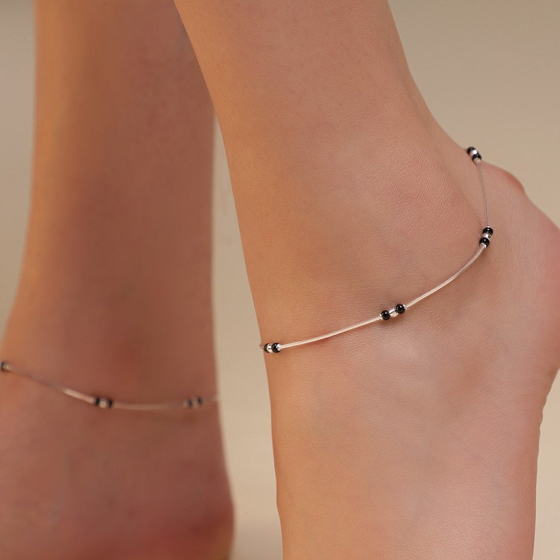 Woman wearing a delicate 925 Sterling Silver anklet with black beads. Silver jewellery for women – Zavya