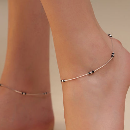 Woman wearing a delicate 925 Sterling Silver anklet with black beads. Silver jewellery for women – Zavya