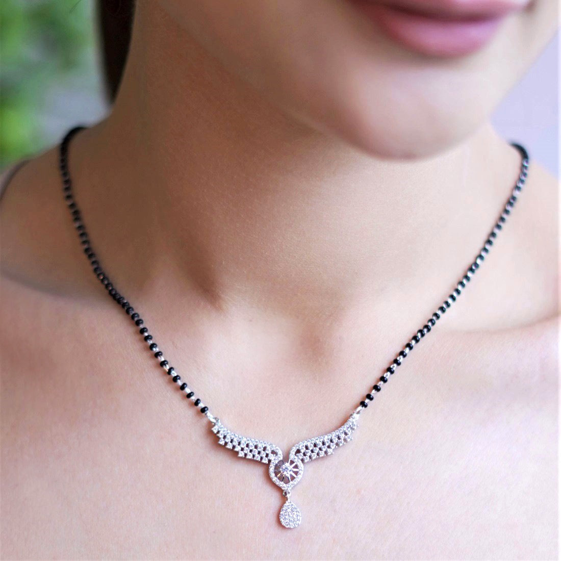 Woman wearing a 925 Sterling Silver black bead mangalsutra necklace with angel wings pendant for women – Zavya