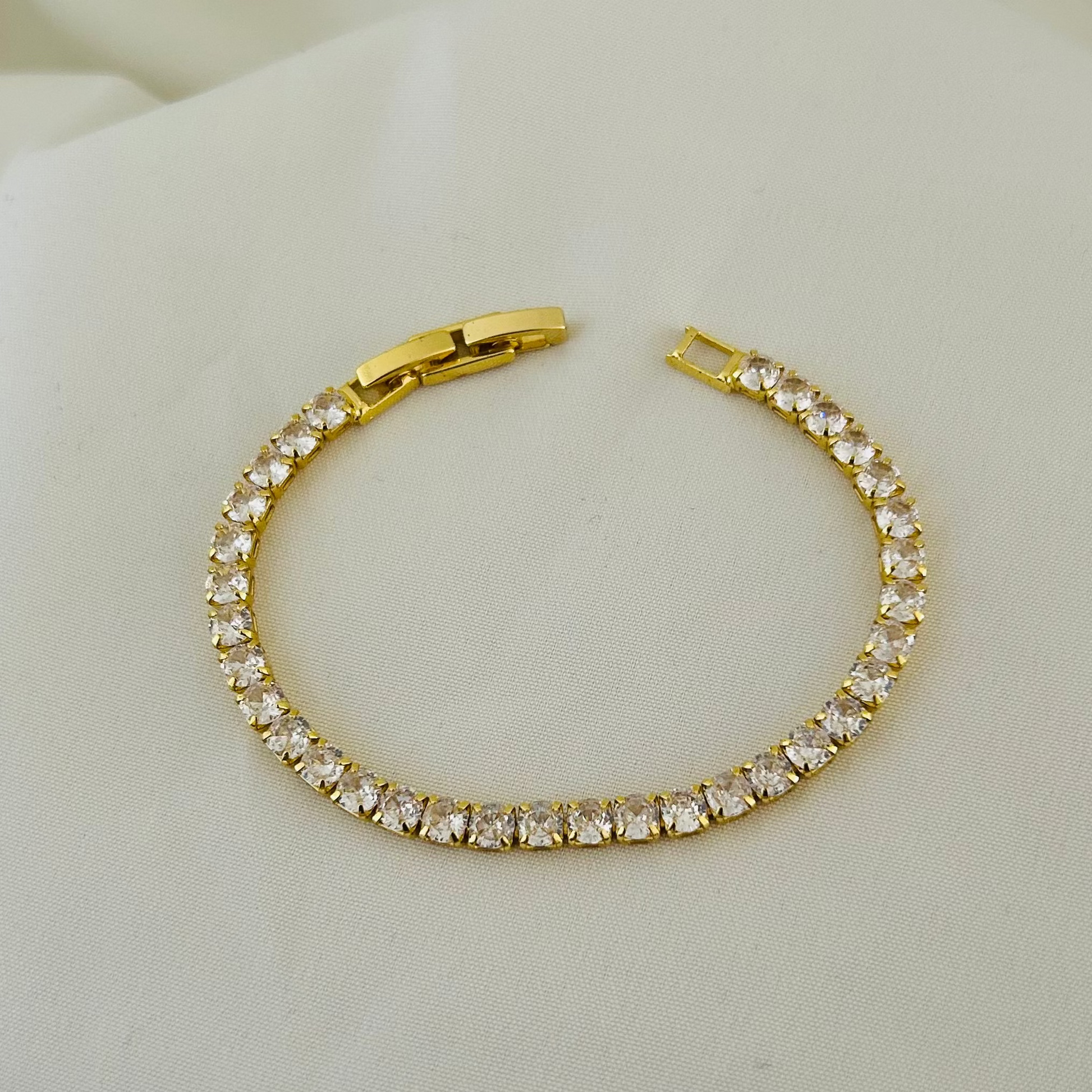 Gold tennis bracelet with white stones on white background